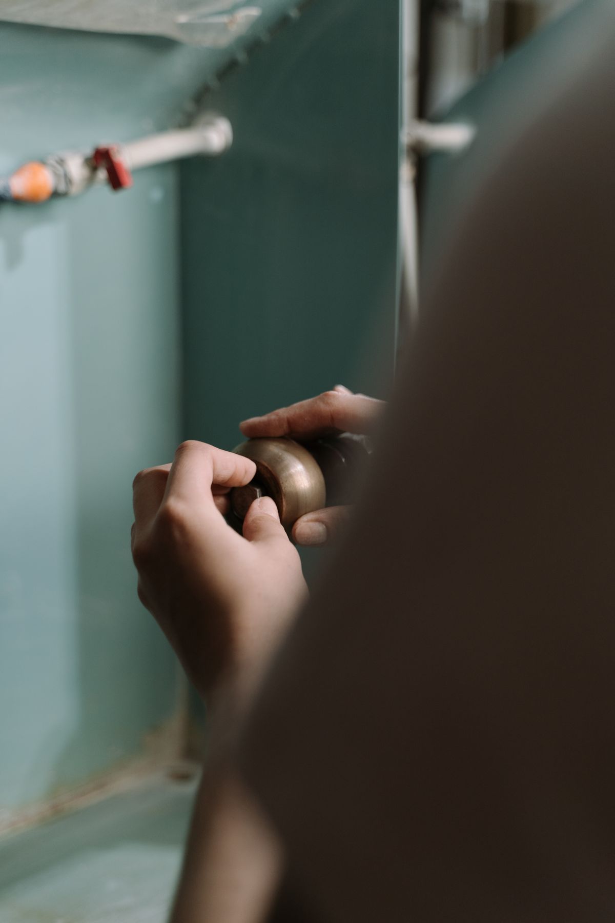 Plumber's hands adjusting a pipe fitting under a fixture during a burst pipe repair in Mesa and Phoenix Metro Arizona