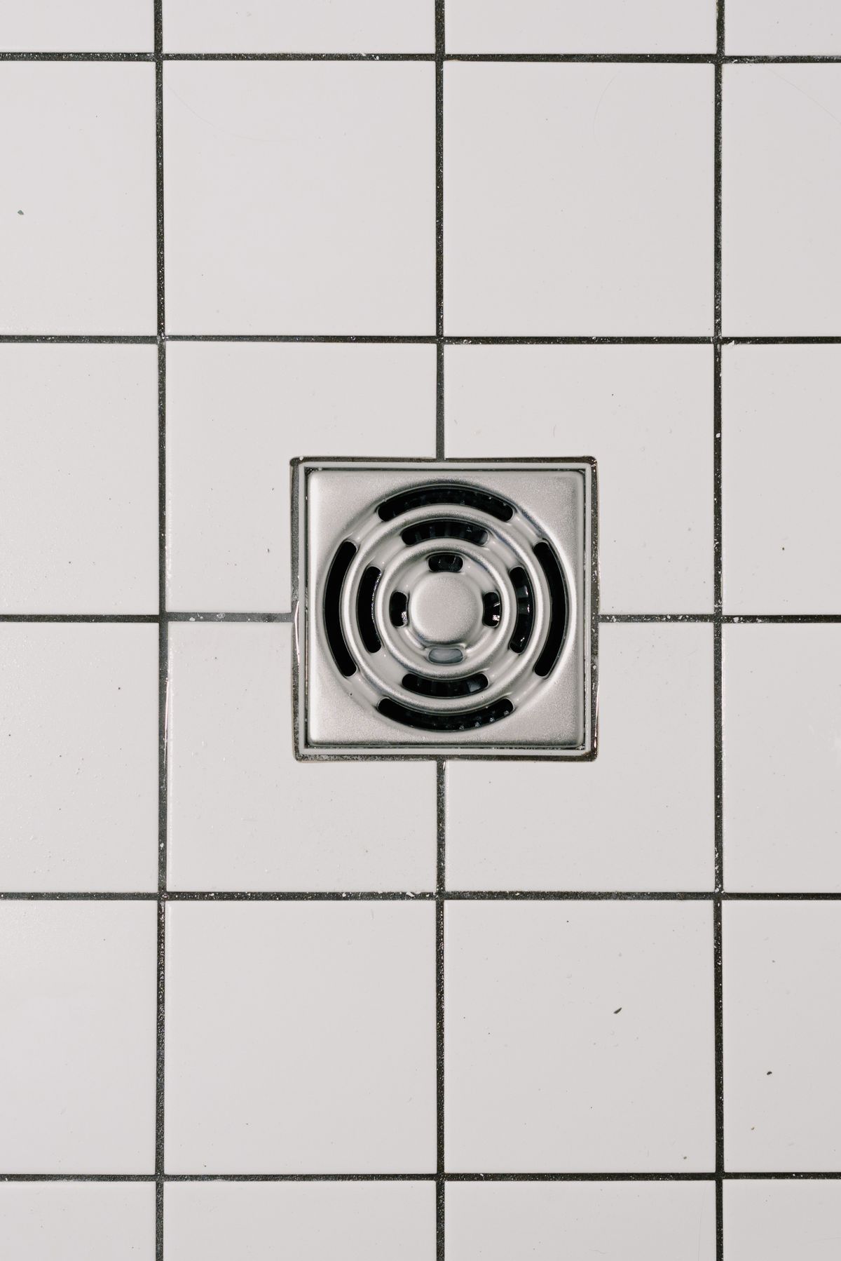 Modern shower drain cover on tile floor before a clogged shower drain cleaning in Scottsdale and Phoenix Metro Arizona