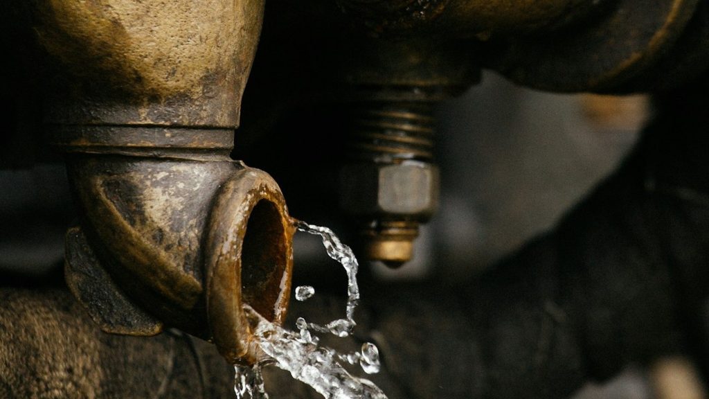 Water leaking from a corroded pipe fitting, a sign of a slab leak